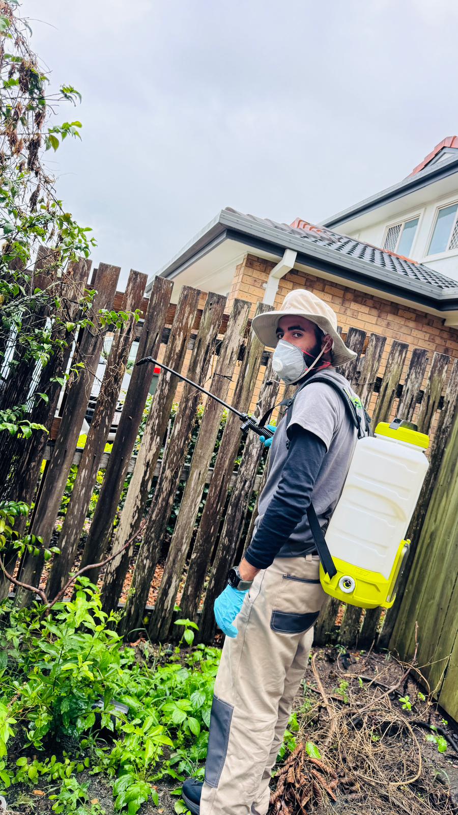 Pestigo technician performing garden-edge pest control treatment